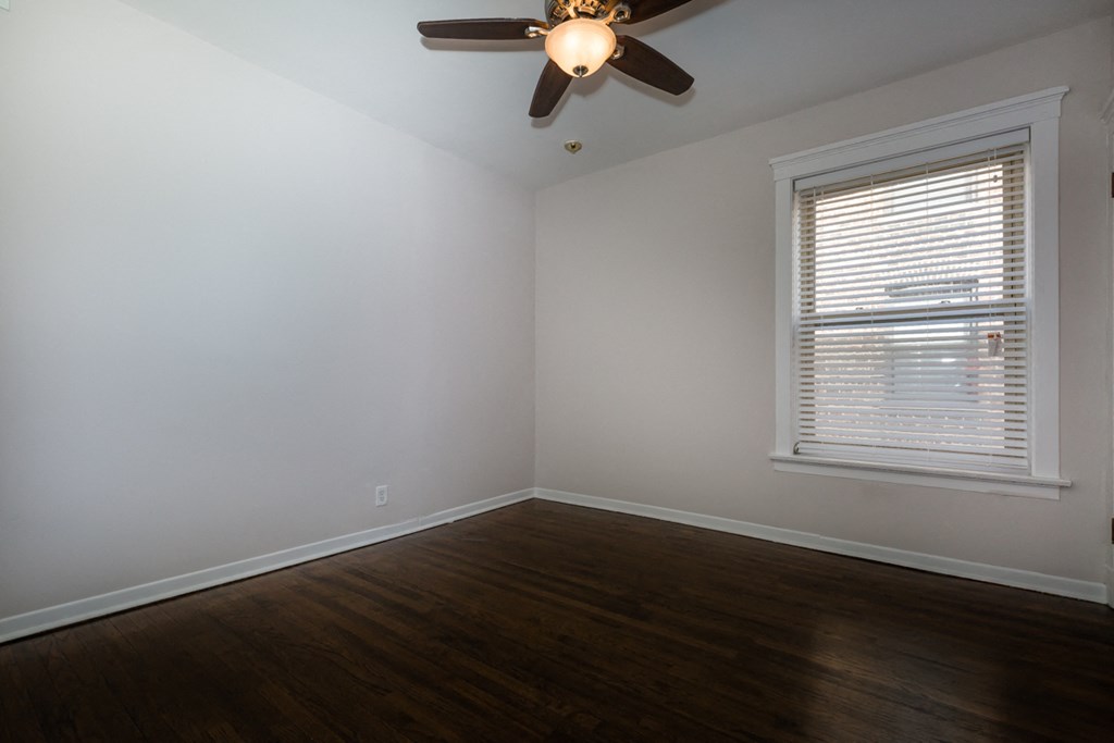 an empty room with a ceiling fan and a window