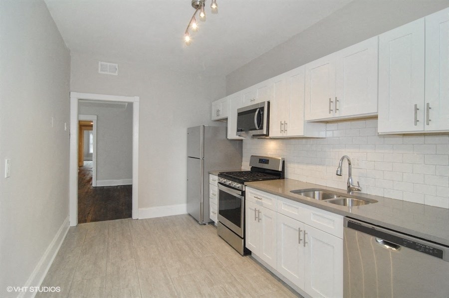 an empty kitchen with white cabinets and stainless steel appliances