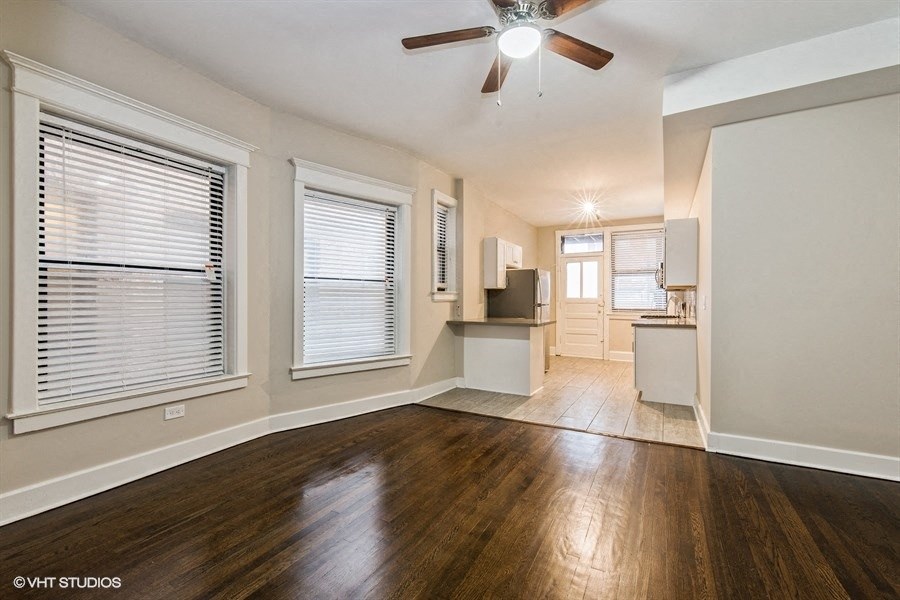 an empty living room with wood floors and a ceiling fan