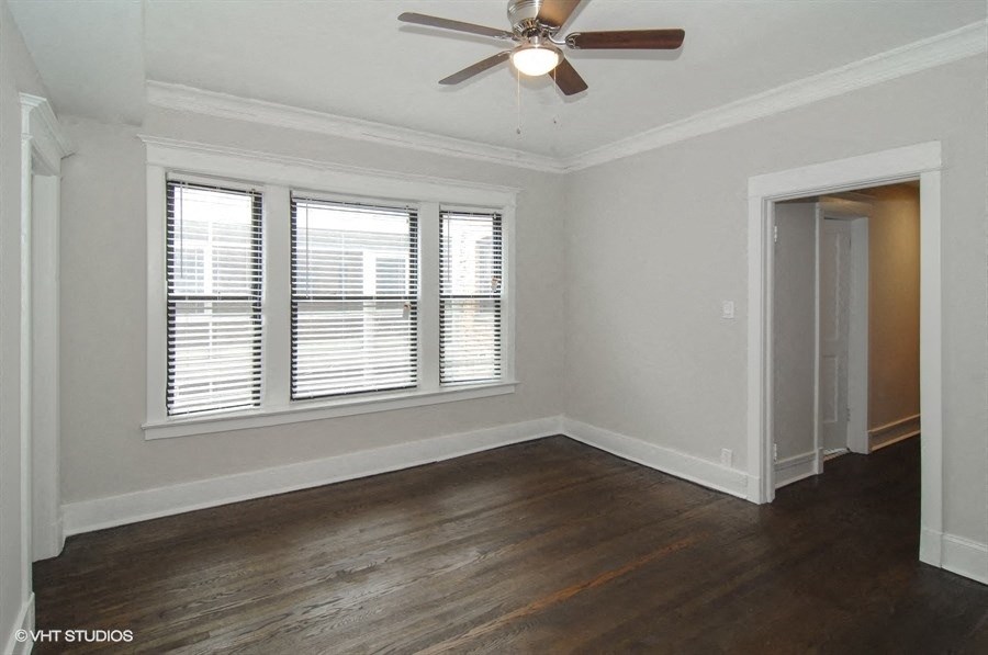 an empty living room with a ceiling fan and three windows
