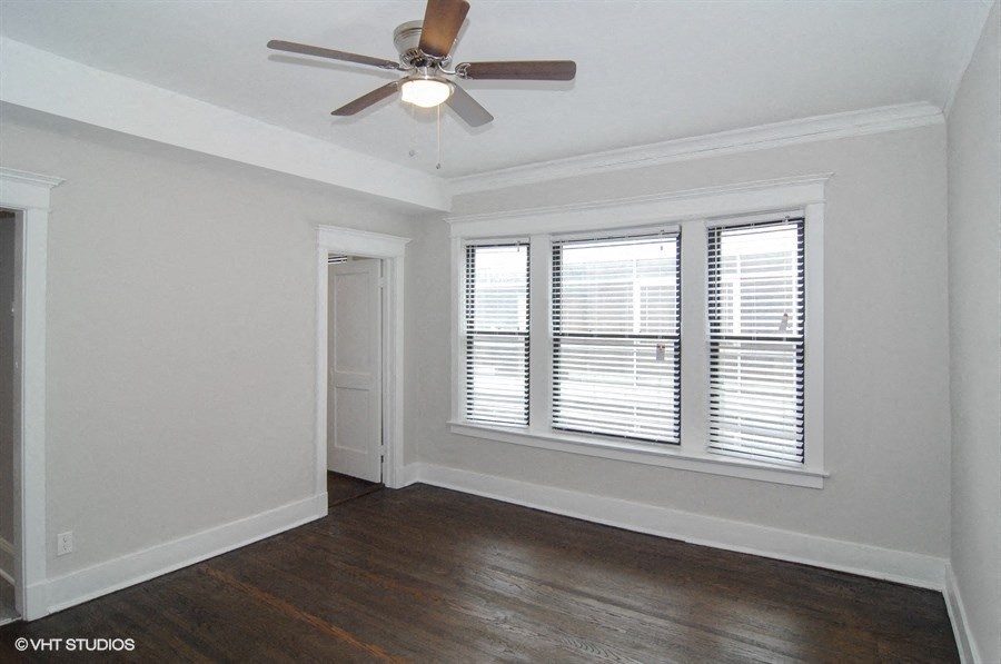 an empty living room with a ceiling fan and a window