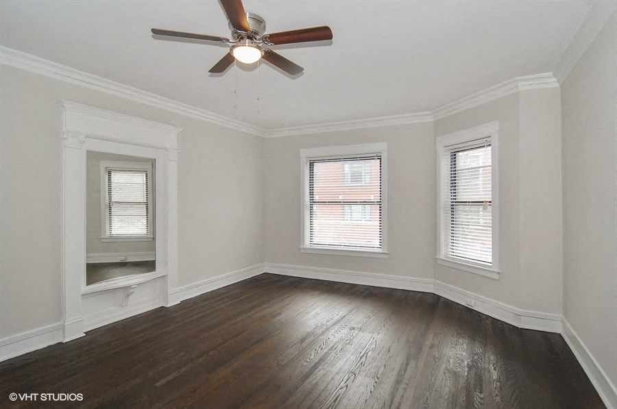 an empty living room with a ceiling fan and three windows