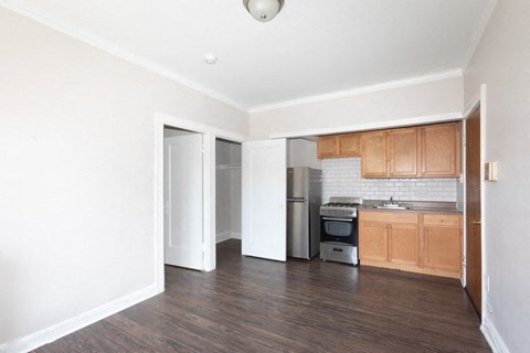 an empty living room and kitchen with wood floors and white walls