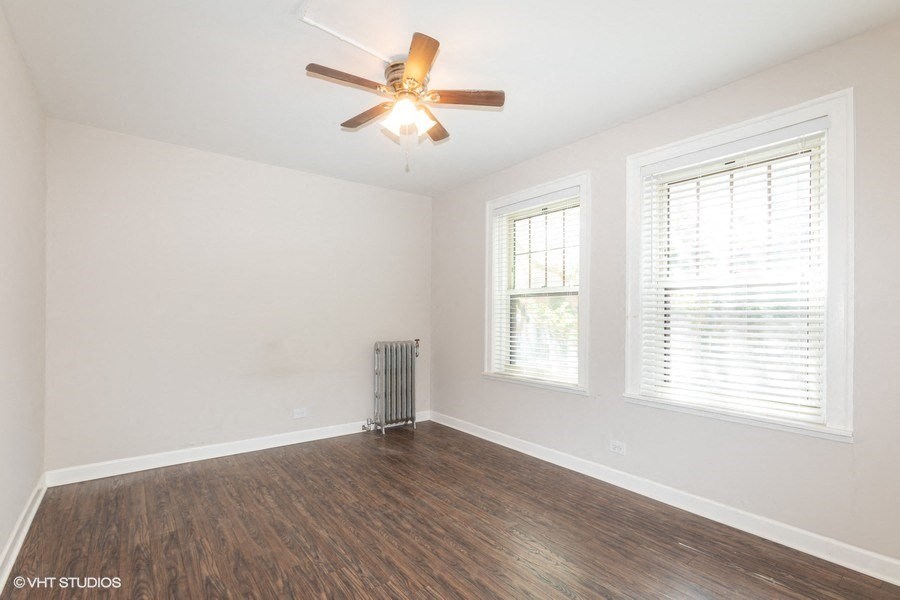 an empty living room with a ceiling fan and two windows
