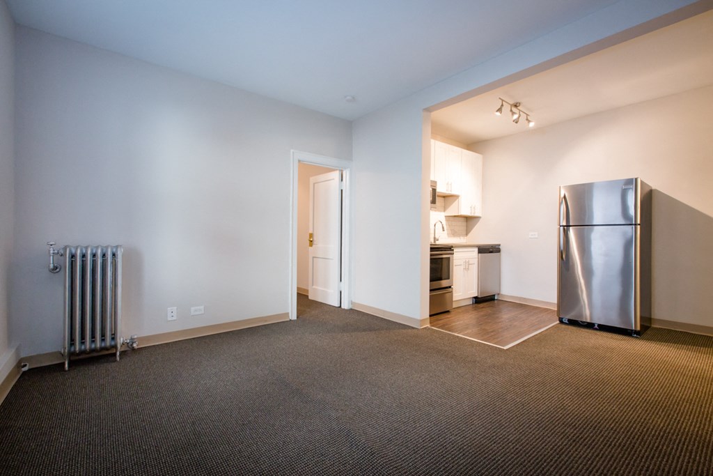 a living room with a refrigerator and a kitchen