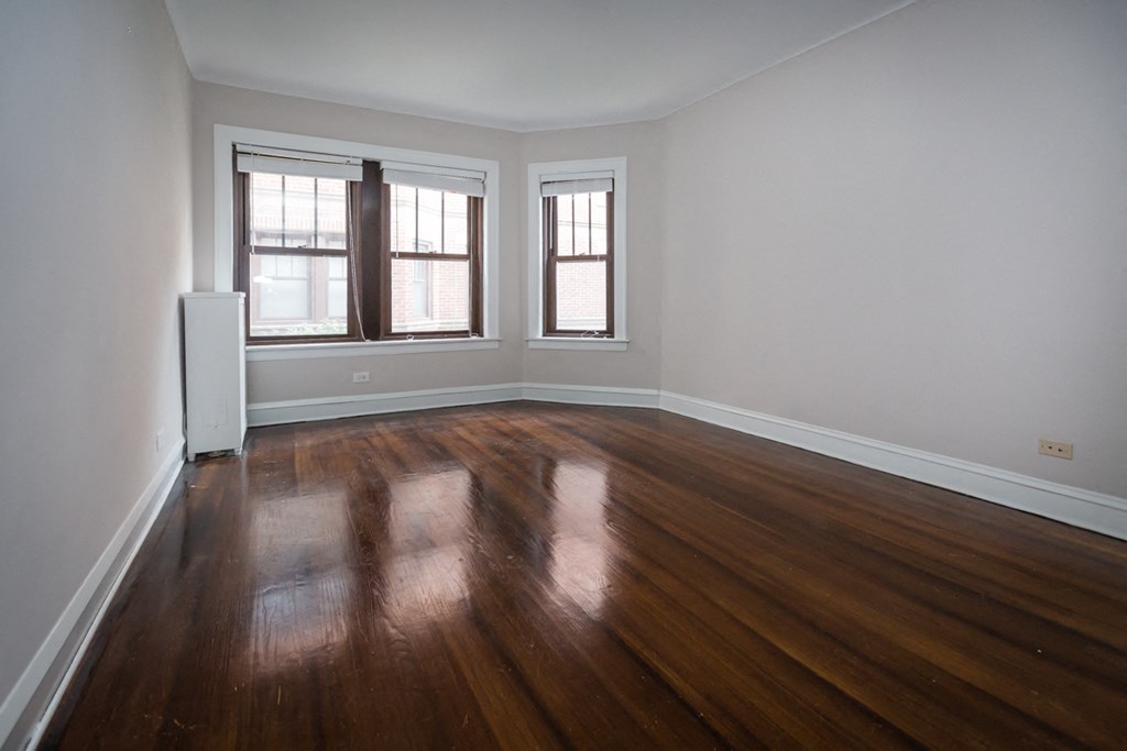an empty living room with wooden floors and windows