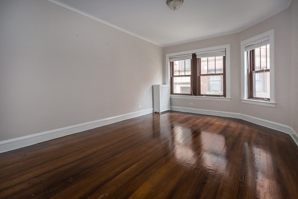an empty living room with wood floors and a window
