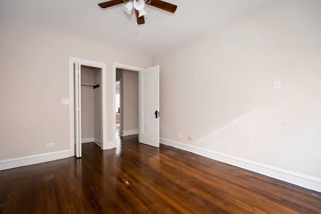 an empty living room with wood floors and a ceiling fan
