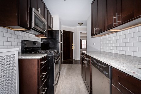 a kitchen with black appliances and white tiles and wooden cabinets