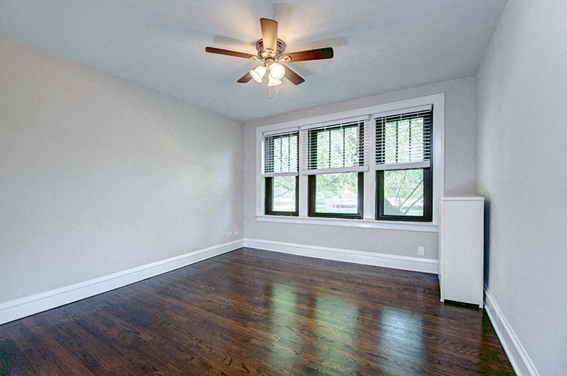 an empty living room with a ceiling fan and a window