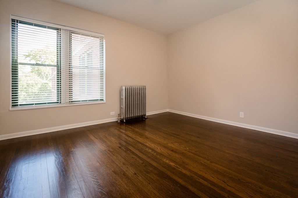 an empty living room with wood floors and a radiator