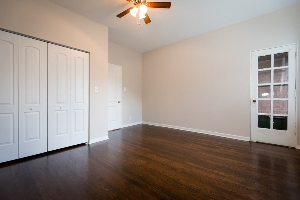 an empty living room with wood floors and a ceiling fan
