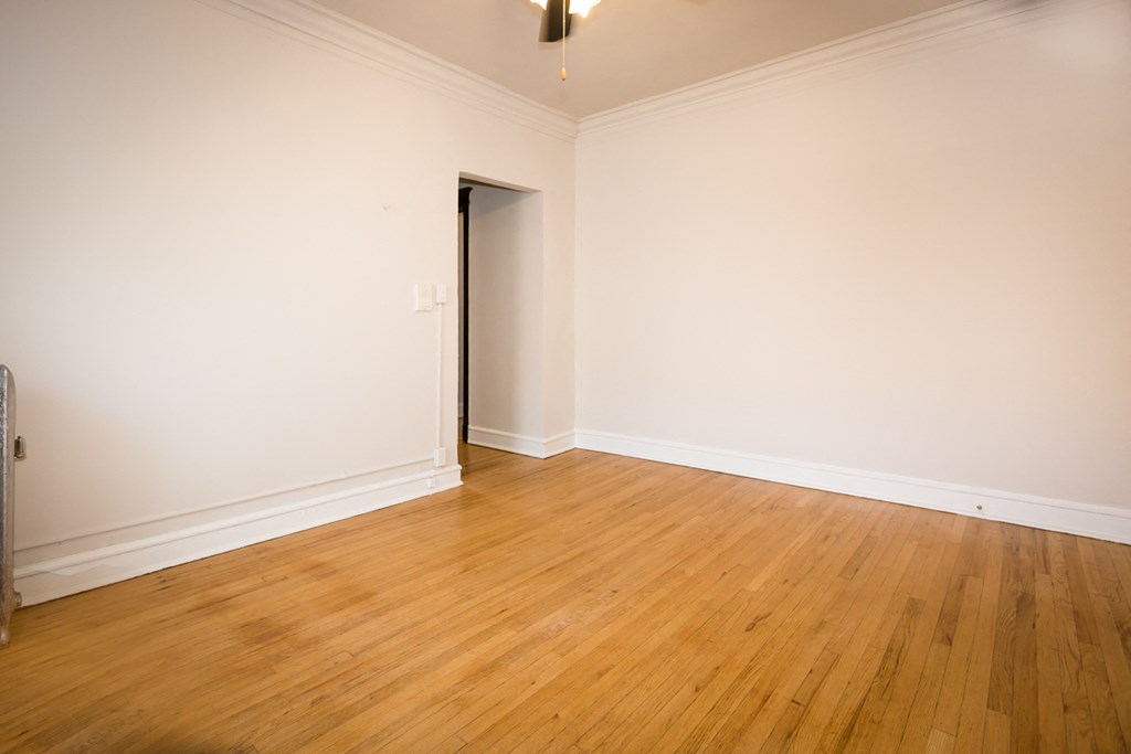 an empty living room with wood floors and white walls