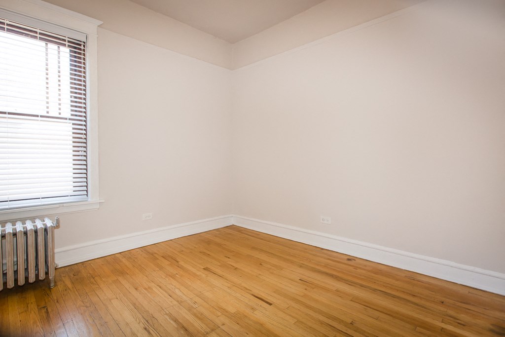 an empty room with wooden floors and a window