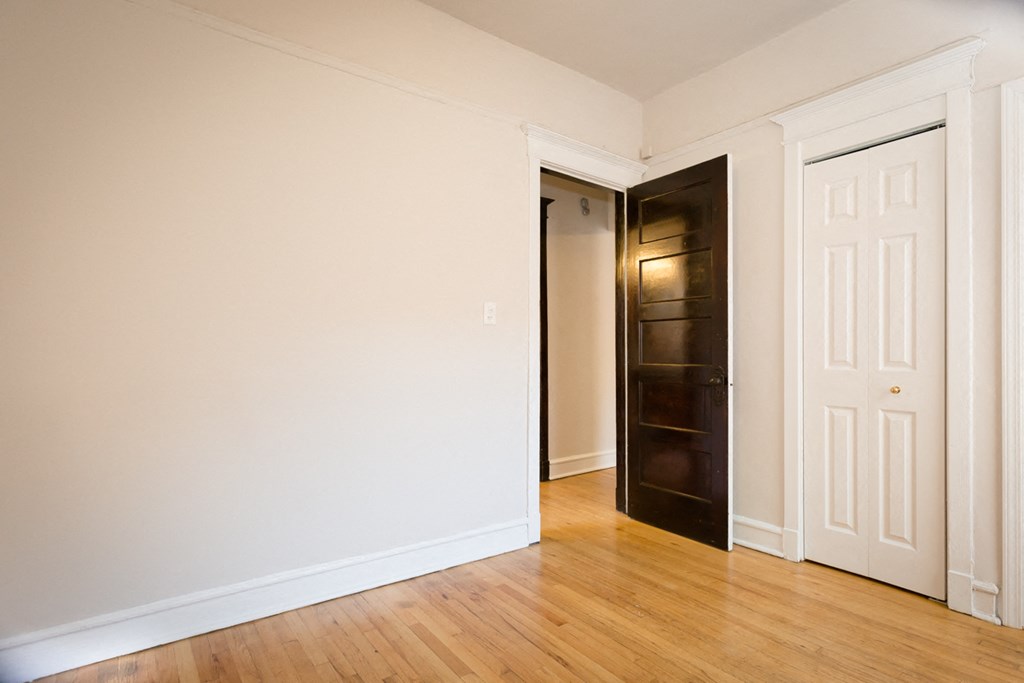 an empty living room with wood floors and a black closet