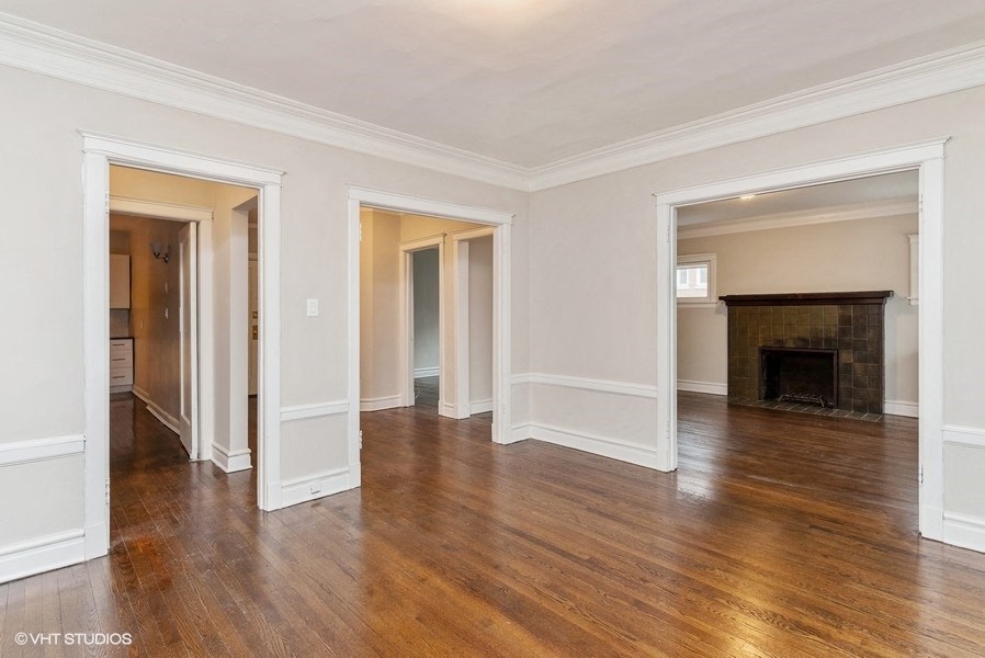 the living room and dining room of a house with wood floors and a fireplace