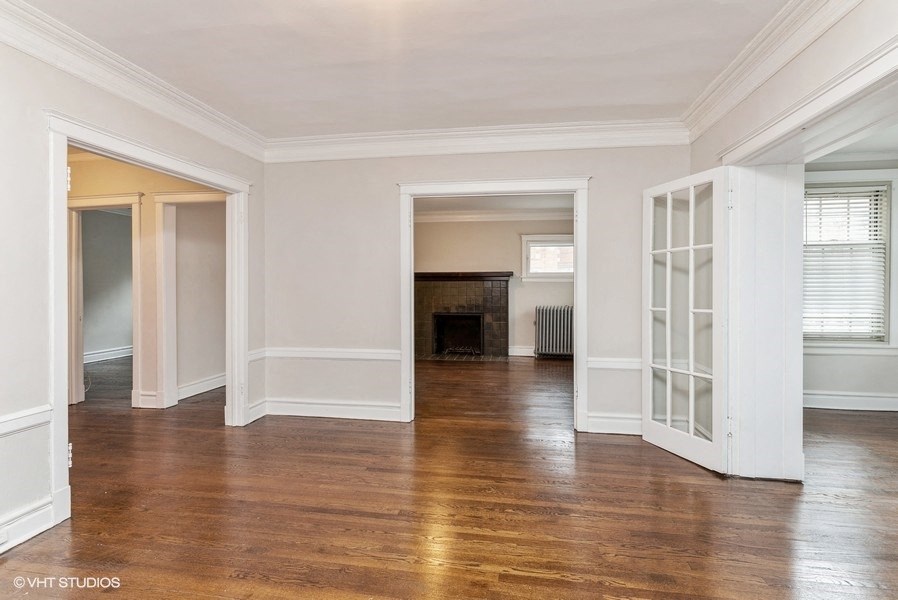 the living room and dining room of a house with white walls and a fireplace