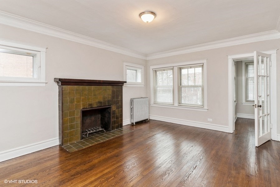 an empty living room with a brick fireplace and wooden floors