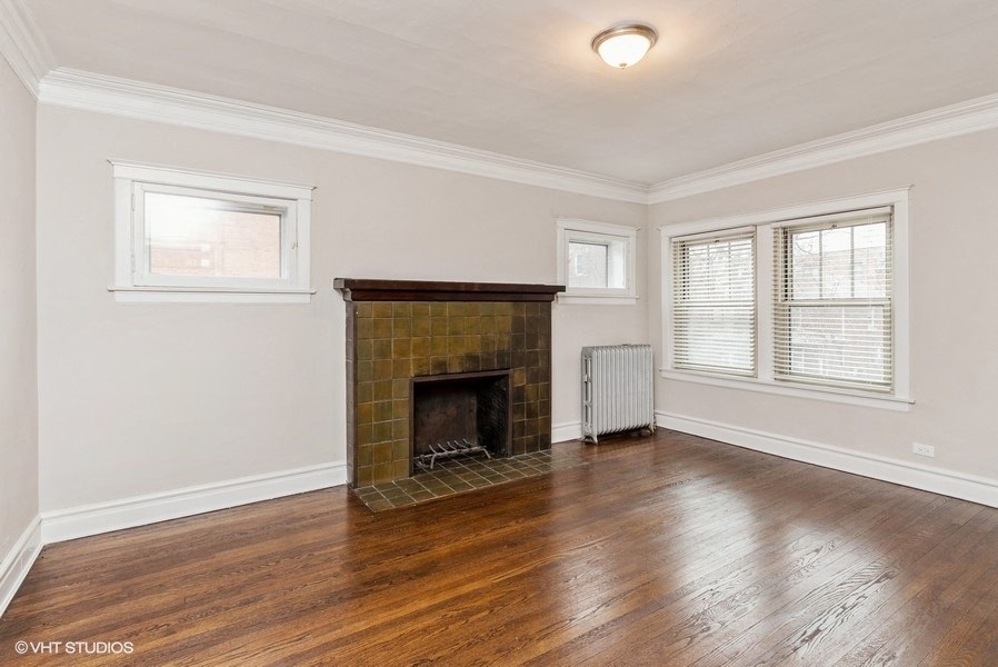 an empty living room with a brick fireplace and wooden floors