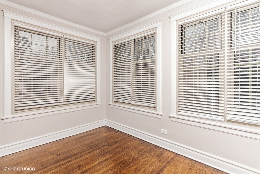a living room with three windows and a wood floor
