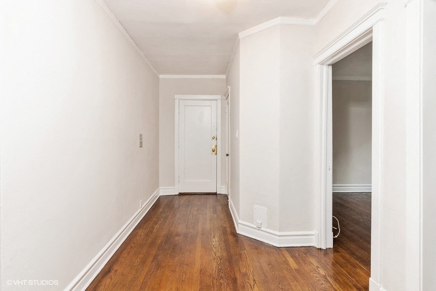 a bedroom with white walls and wood floors and a closet