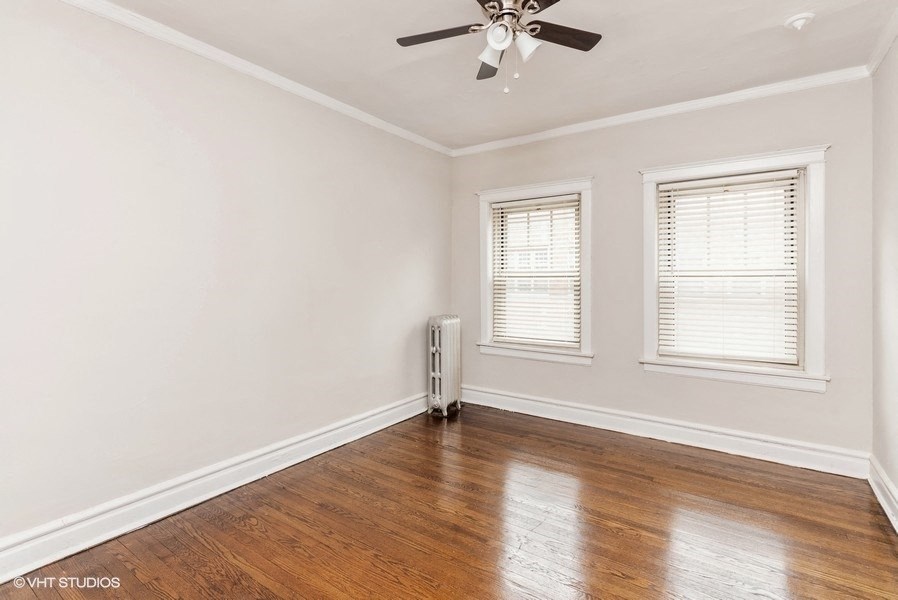 an empty room with a ceiling fan and two windows