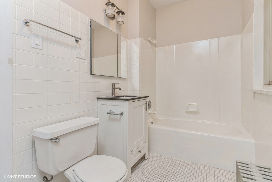 a white bathroom with a toilet and a bath tub