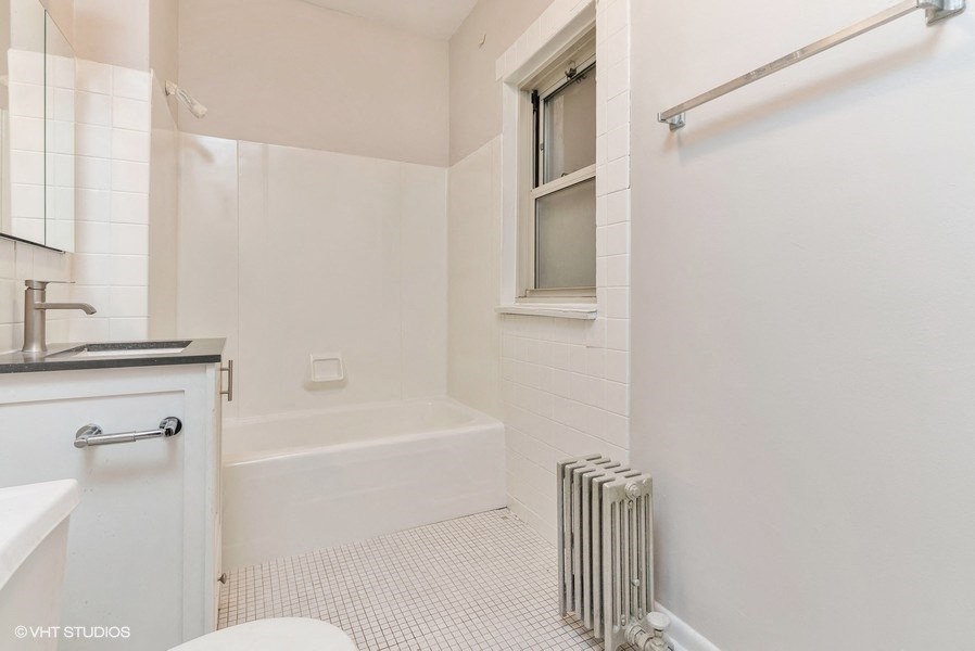 a white bathroom with a tub and a sink and a window