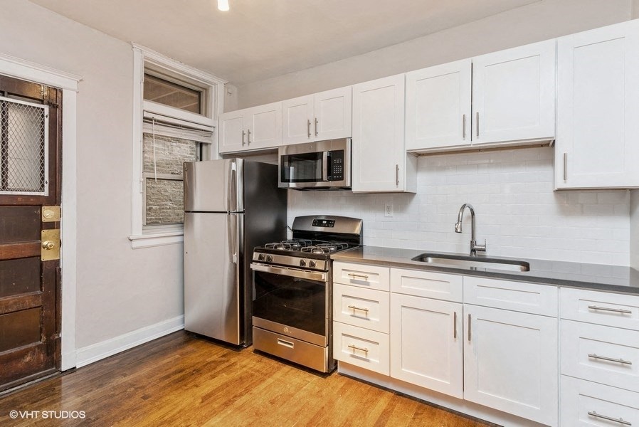 a kitchen with white cabinets and a stainless steel refrigerator