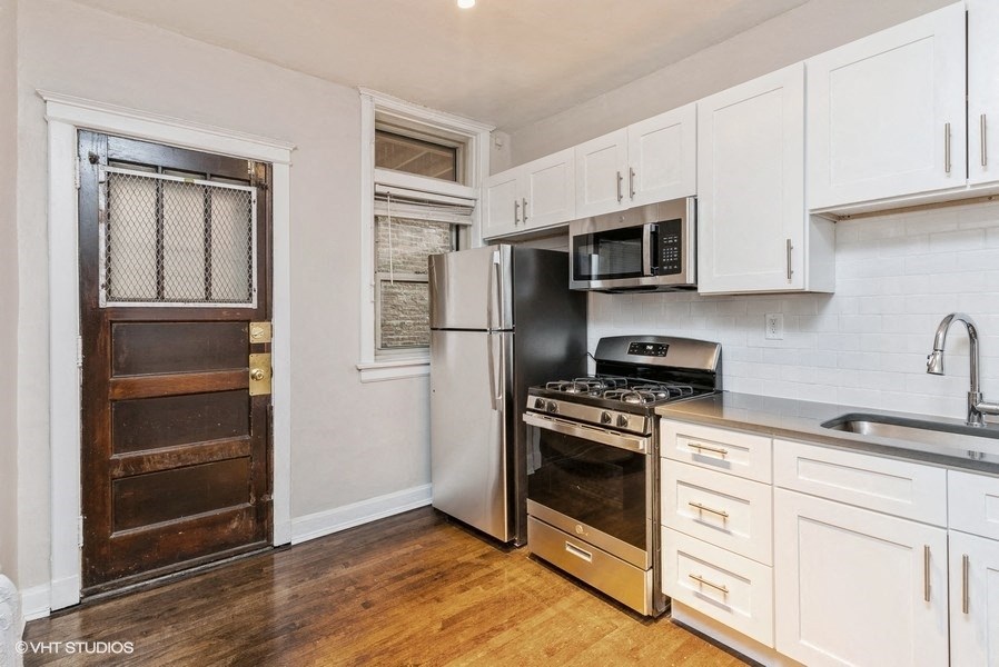 a kitchen with white cabinets and a stainless steel refrigerator