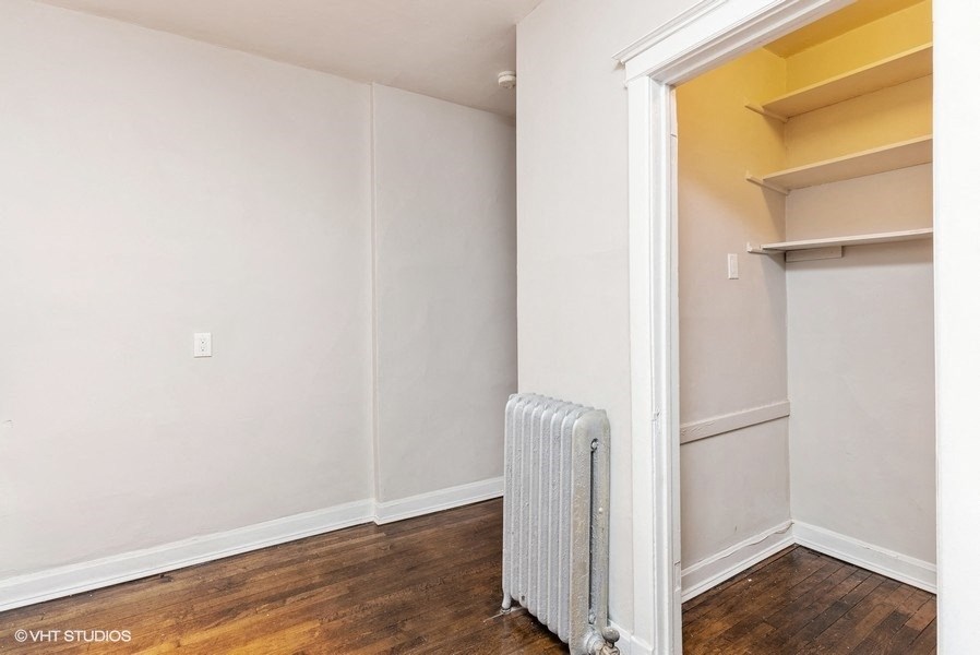 a room with white walls and a closet and a radiator