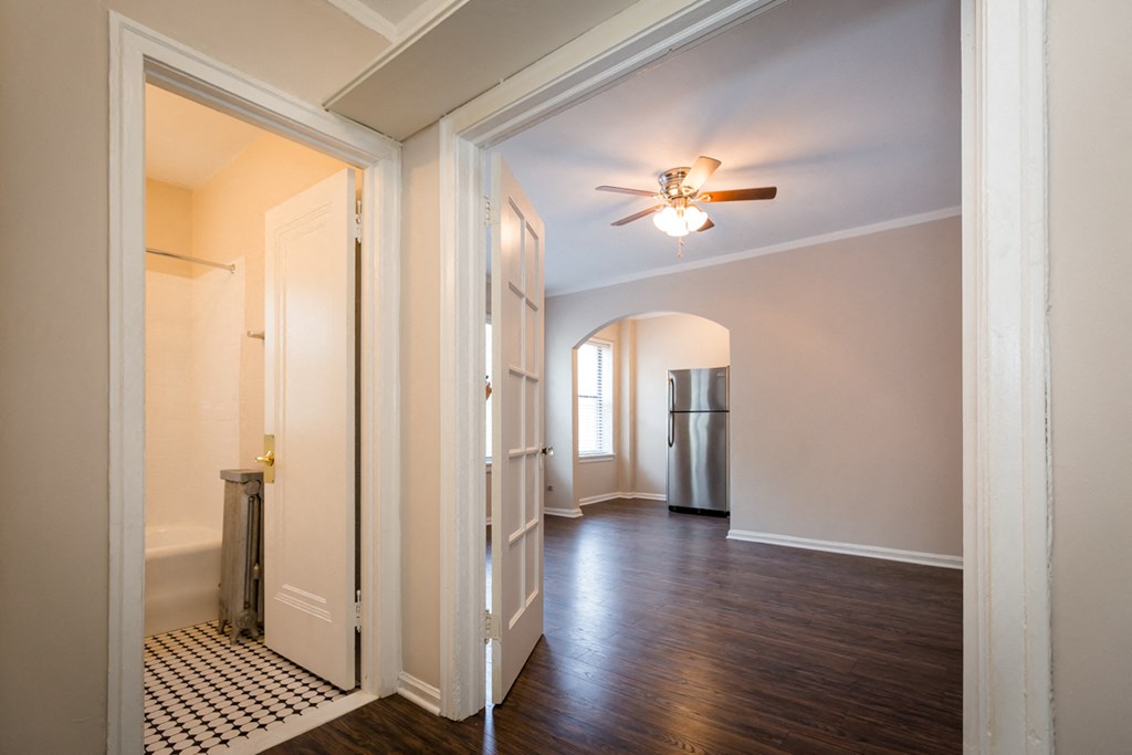 an empty living room with a ceiling fan and a door to a kitchen