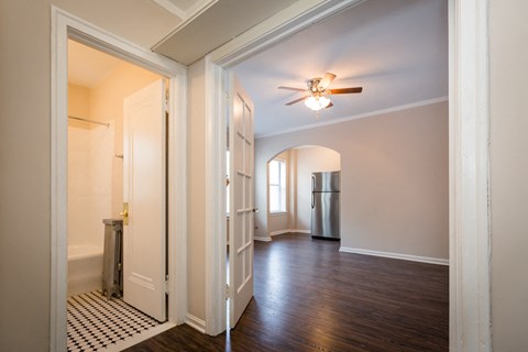 an empty living room with a ceiling fan and a door to a kitchen