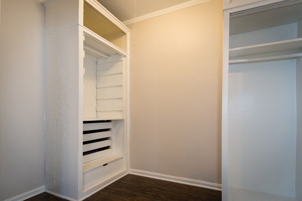 a walk in closet in a home with white walls and shelves