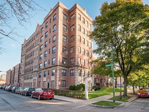 a tall brick building with cars parked in front of it