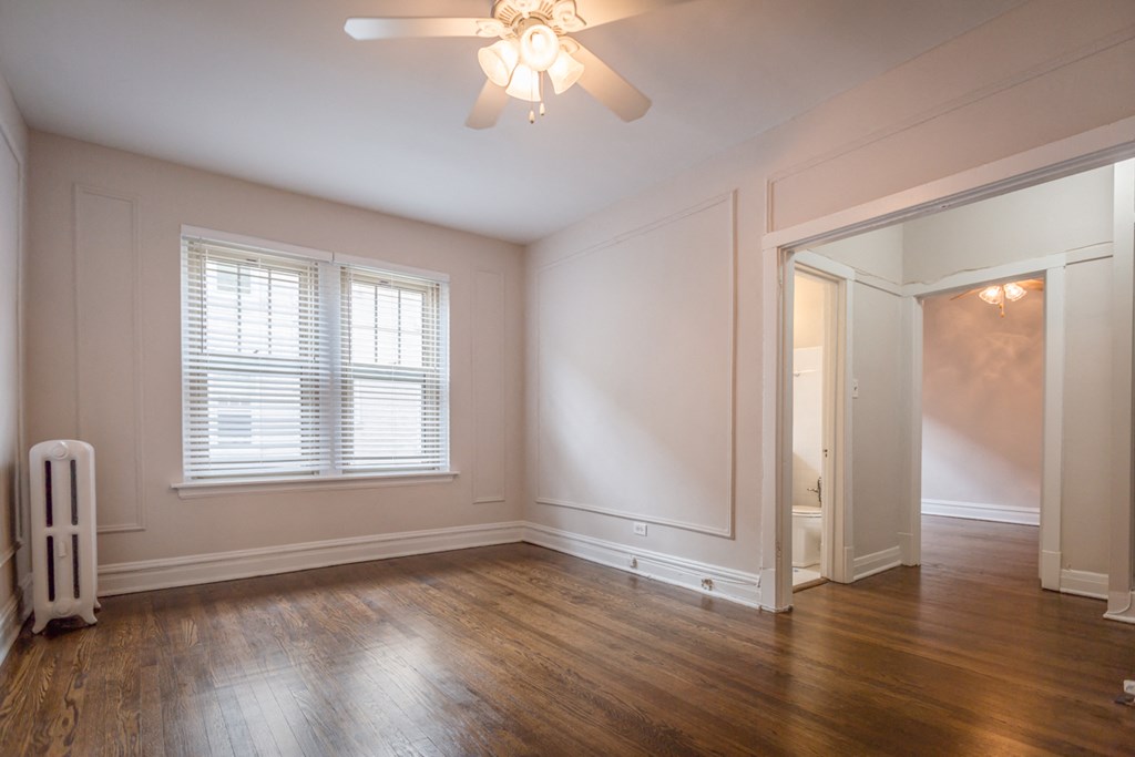 an empty living room with wood floors and a ceiling fan