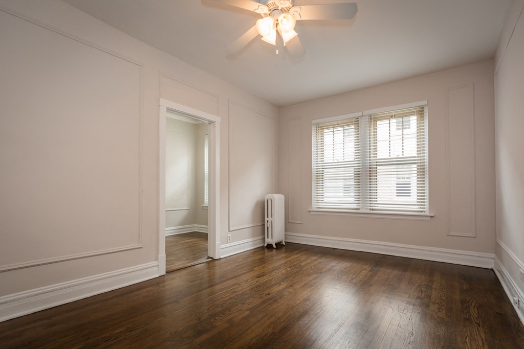 an empty living room with wood floors and a ceiling fan