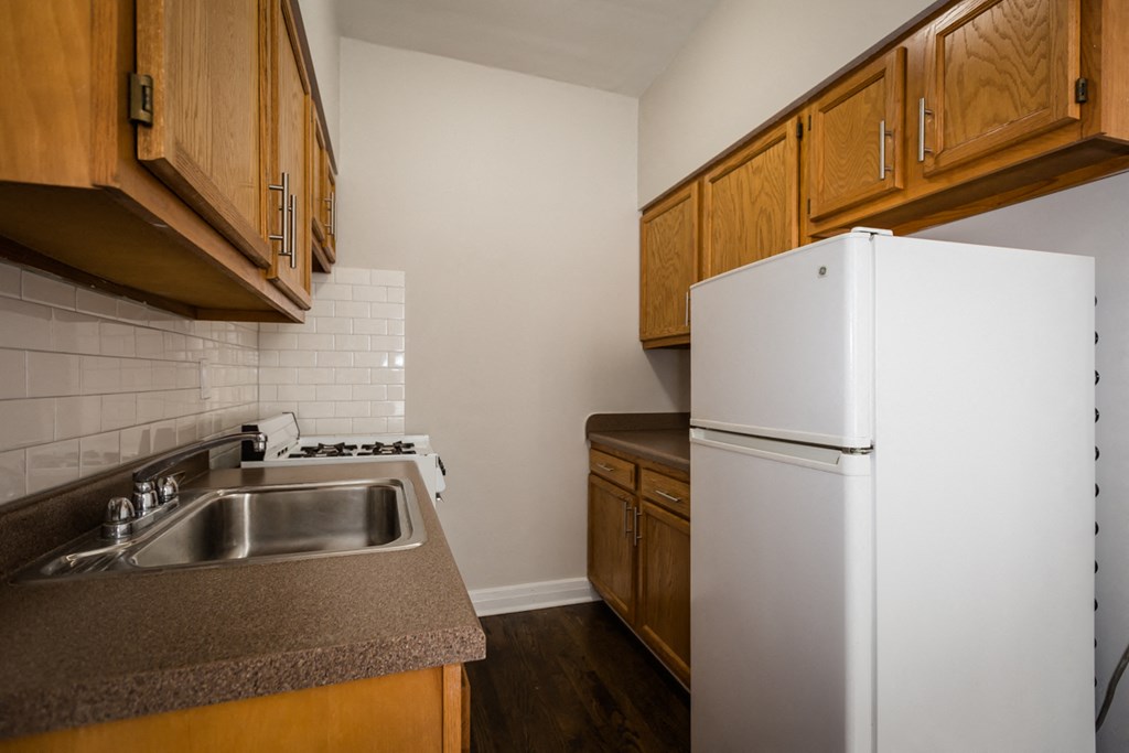 a kitchen with a sink and refrigerator and wooden cabinets