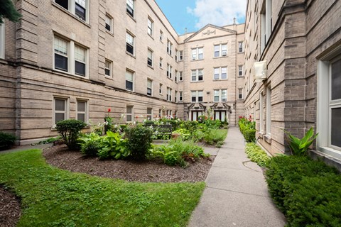 a walkway between buildings with a garden in the middle