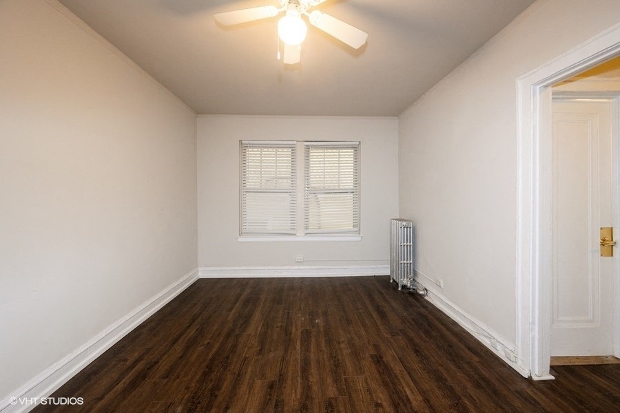 the spacious living room with hardwood flooring and a ceiling fan
