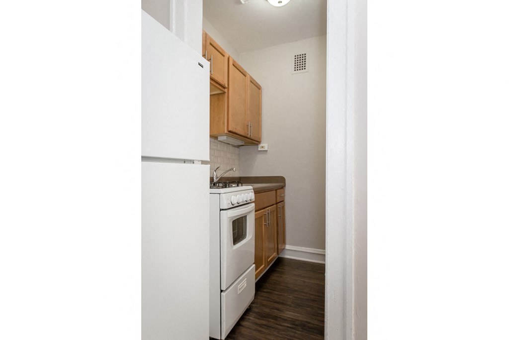 an empty kitchen with a white stove and refrigerator