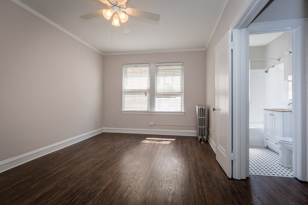 an empty living room with wood floors and a ceiling fan