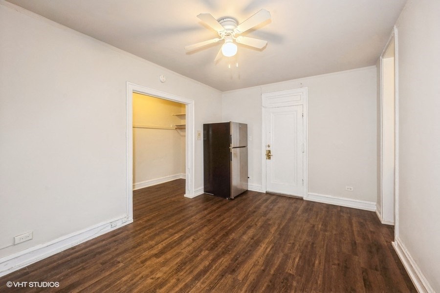 an empty living room with a refrigerator in the corner