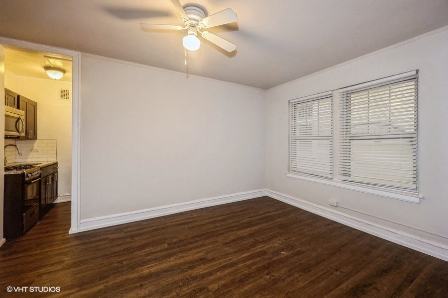 an empty living room with a ceiling fan and a window