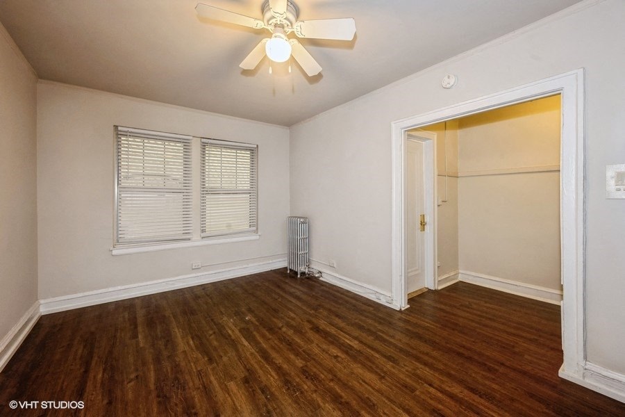 the living room of an empty home with wood flooring and a ceiling fan
