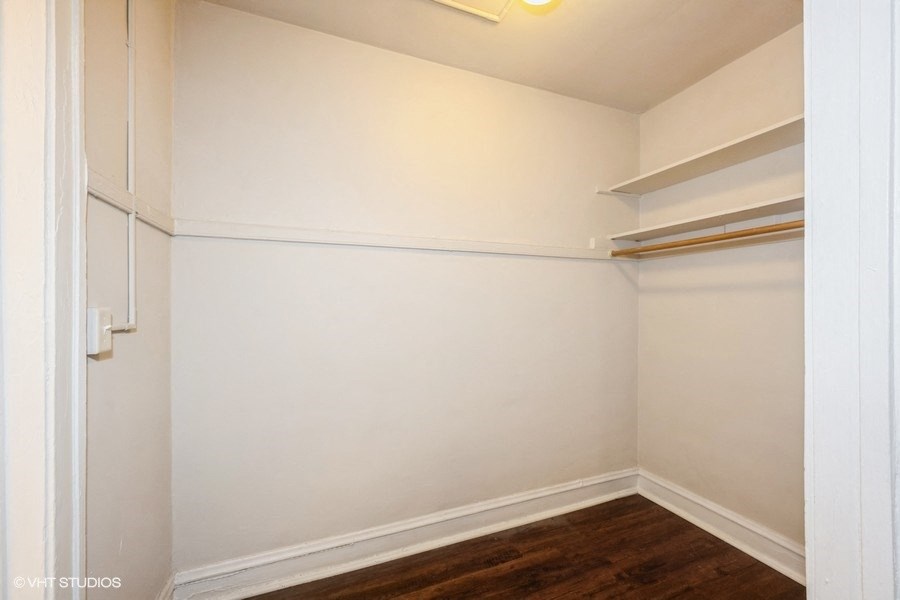 a room with white walls and shelves and a wood floor