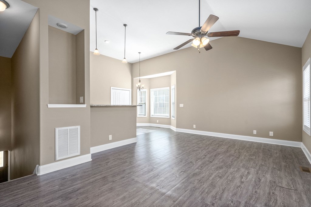 an empty living room with a ceiling fan