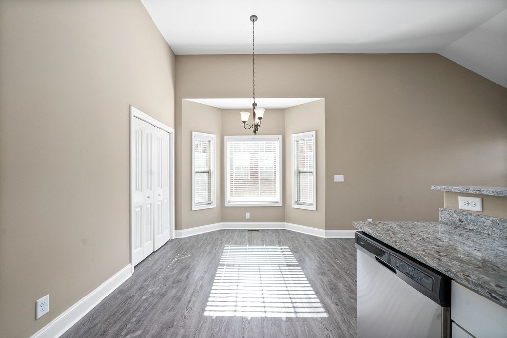 an empty living room with a kitchen and a window