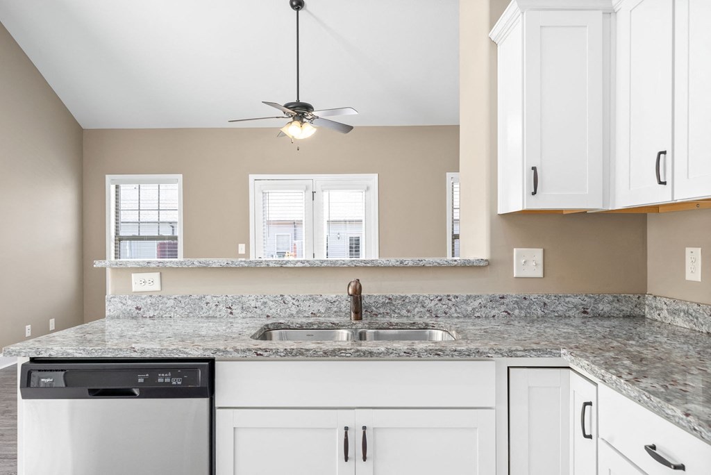 a kitchen with white cabinets and a sink and a ceiling fan
