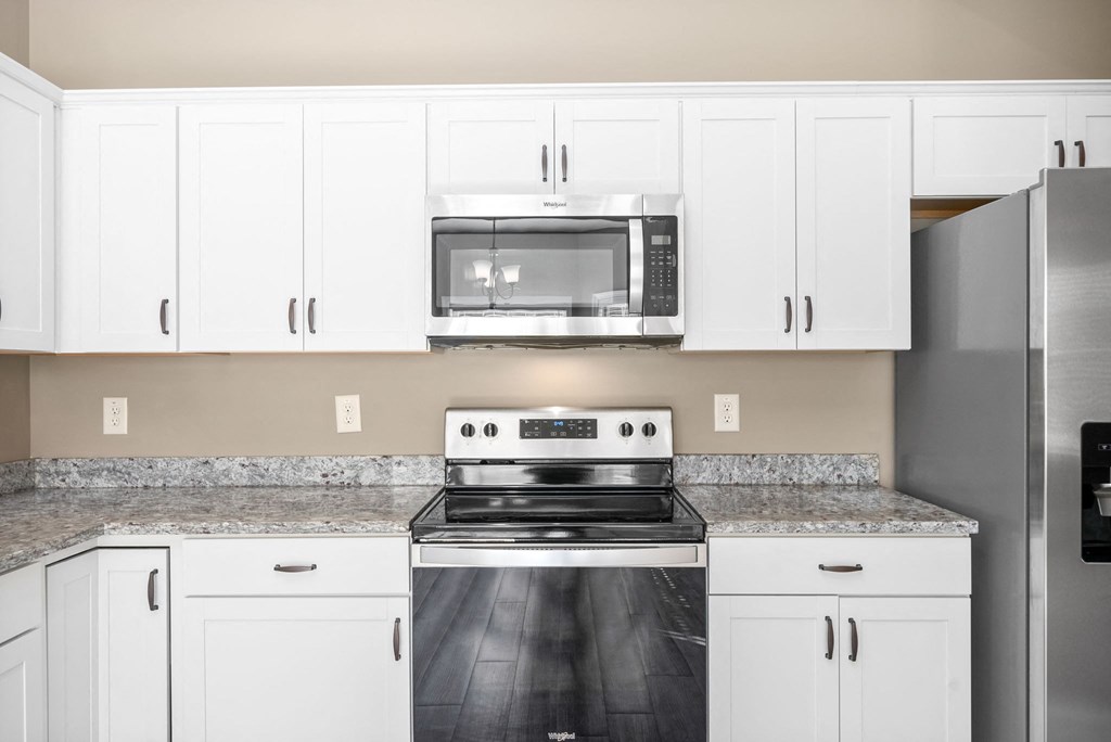 a kitchen with white cabinets and a stove and a microwave